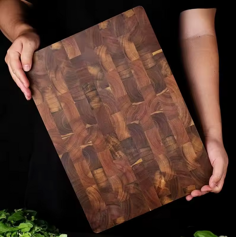Wooden cutting board with a woven pattern held by two hands on a black background